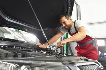 Automechaniker repariert Fahrzeug in einer Werkstatt // Auto mechanic repaired vehicle in a garage