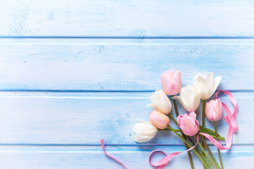 Obraz na płótnie Canvas Spring white and pink spring tulips and pink ribbon on blue w