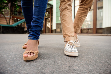 Fototapeta na wymiar Close up of couple's legs in keds walking down street.