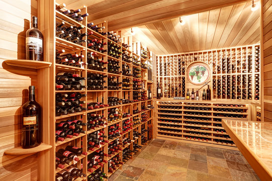 Bright Home Wine Cellar With Wooden Storage Units With Bottles.