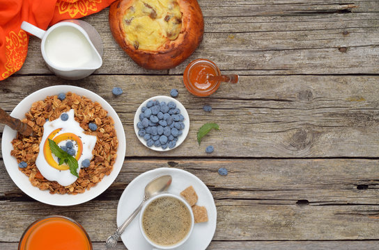 Breakfast table with granola, milk, berries and juice with text space, top view.