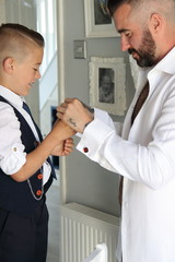 Obraz premium A young boy dressing his father on his wedding day as part of his best man duties