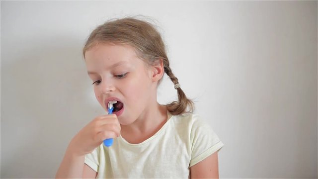A little girl brushing her teeth with a brightly colored toothbrush
