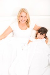 Fototapeta premium A mother relaxing in bed with her daughter..