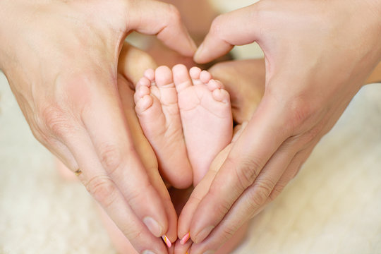 baby feet in mom's and dad's hands with a blurred background