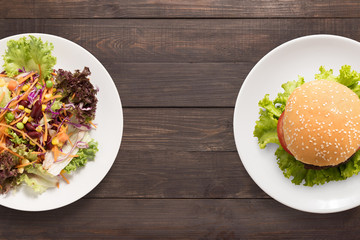 Fresh salad and burger on the wooden background. 