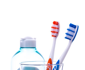Zahnbürsten in Wasserglas mit Kosmetik Flasche isoliert auf wei