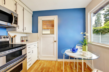 Kitchen room with white cabinets, blue walls and glass able