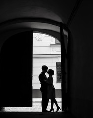 Silhouettes of cute couple hugging in the end of dark alley