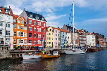 Fototapeta na wymiar September, 24th, 2015 - Copenhagen, Denmark. Nuhavn harbor with colorful scandinavian houses and private boats reflected on the water of canal.