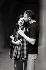 Man lies his plaid shirt on woman's shoulders and kisses her hea