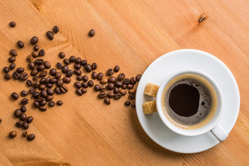 Coffee cup, sugar and coffee beans on wooden background.