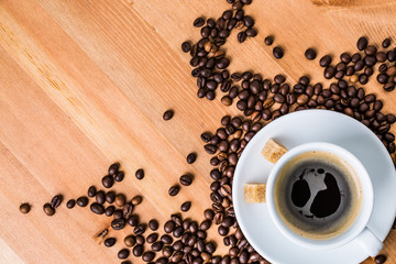Coffee cup, sugar and coffee beans on wooden background.