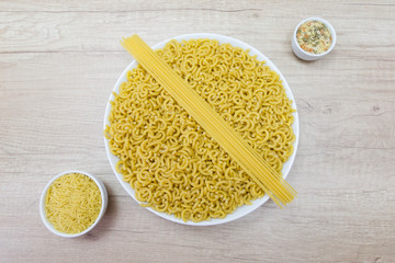 bowls of fideuá, noodles, pasta stars and spaghetti on a wooden table
