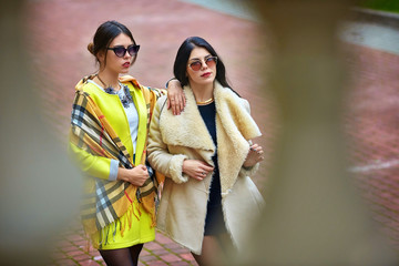 Girl in yellow coat lies her hand over the shoulder of another m