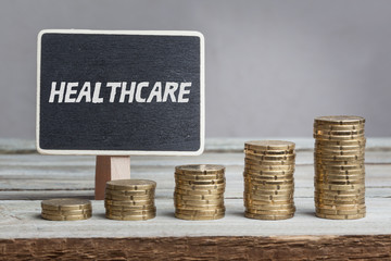 Englisches Wort Healthcare auf Schild, Geld Wachstum, Studiofoto auf Holztisch