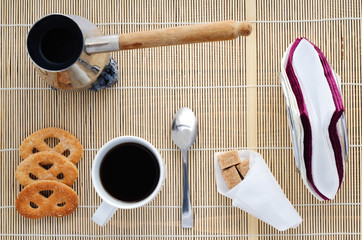 Cup of coffee on a bamboo napkin, sugar, spoon, biscuits, napkin, top view
