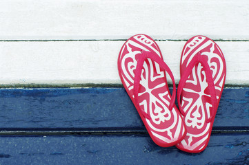 Red flip flops on a blue and white wooden painted board