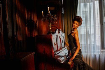 Fototapeta na wymiar Thing model in black gown puts her hands on piano keys