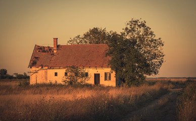 Vintage photo of abandoned house in sunset