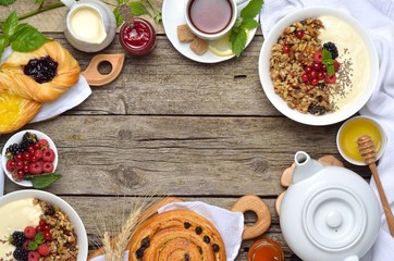 Homemade granola and various delicious ingredients for a healthy breakfast - fresh berries, yogurt, honey, tea on wooden background. Copyspace background.Top view.