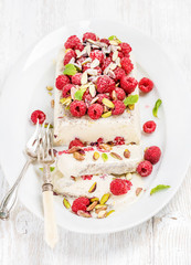 Homemade semifreddo with pistachio and raspberry in oval dish over old white painted wooden background, selective focus, horizontal composition