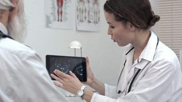 Doctor talks about x-ray on the tablet smiling. Good news.