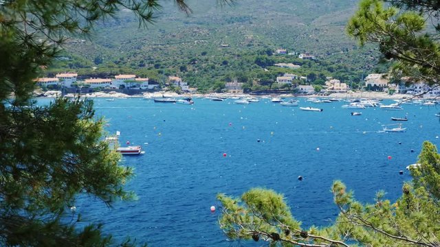 Beautiful view of the sea with yachts and boats. In the foreground trees. On the rocky shore of a small resort town in Spain