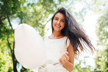 Bottom view of beautiful young woman smile with cotton candy on nature background.