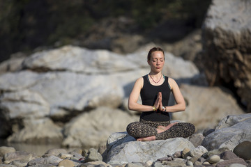 Amazing beautiful girl does yoga near the river.