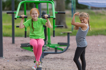 Fototapeta na wymiar Two little cute girls is engaged in sports equipment outdoor.