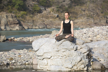 Amazing beautiful girl does yoga near the river.