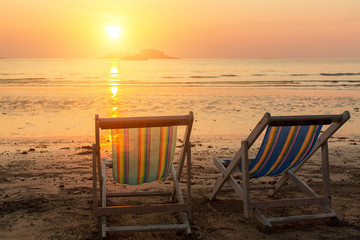 Pair of beach loungers on the sea sunset.