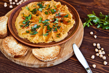 Fresh bowl of homemade hummus with chickpeas, olive oil and parsley. Served with croutons and nuts