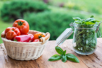 Jar of basil and basket with tomatoes