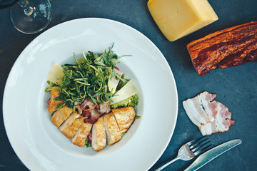 Caesar salad with chicken and greens on black table