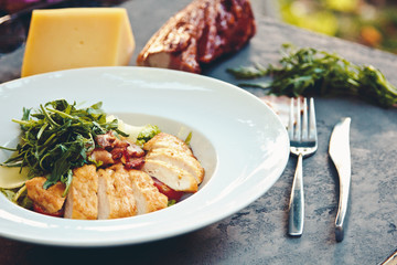 Caesar salad with chicken and greens on black table