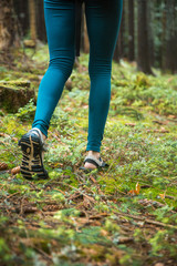 Fototapeta na wymiar Young beautiful girl tourist athletic figure walks in the woods. Female legs walking on forest trail