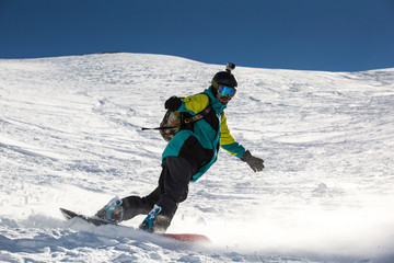 Fototapeta na wymiar Man snowboarder snowboarding on fresh white snow on ski slope on Sunny winter day
