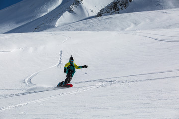 Man snowboarder snowboarding on fresh white snow on ski slope on Sunny winter day