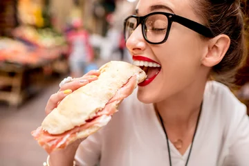 Foto op Plexiglas Young woman sitting with panini sandwich with prosciutto at the cafe outdoor on the street in Bologna city © rh2010