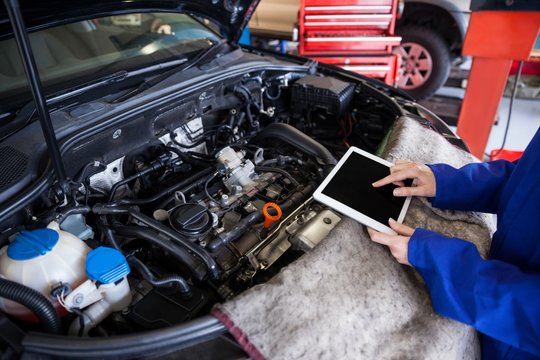 Mechanic using a digital tablet while servicing car engine