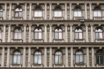 Detail of the facade of a multistory building in classical style with columns and windows.