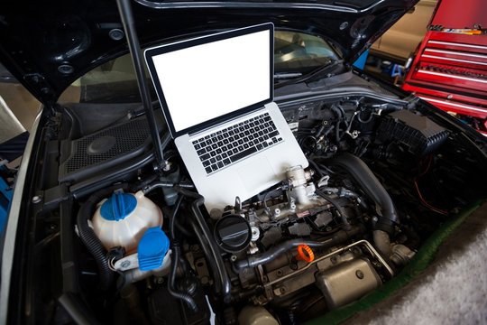 Cars with laptop on open hood for servicing