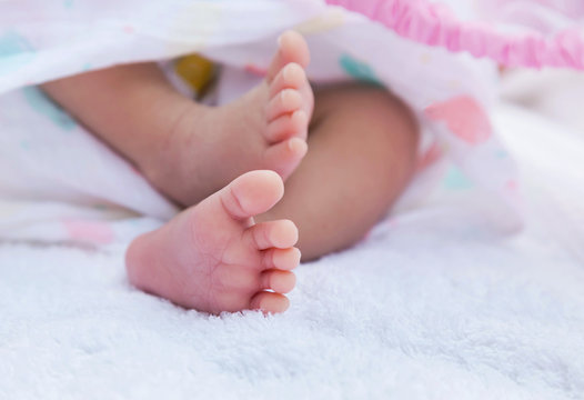 Close up little feet of  baby newborn covered in white towel selective  focus
