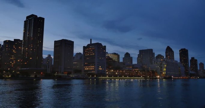 An evening or dusk establishing shot of the midtown Manhattan skyline as seen from Roosevelt Island.  	