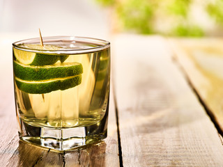 Alcohol drink. On wooden boards standing glass with alcohol green transparent drink. A drink number one hundred eighty three cocktail green tea with slice lime. Country life. Light background.