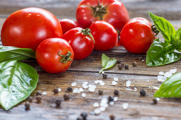 Tomatoes with basil in colander on wooden table background. Food