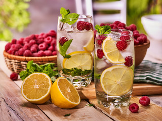 On wooden boards two glasses with ice cubes alcohol cocktail number two hundred one raspberry cocktail mohito with lemon and mint leaf. Country life. Indoor background.