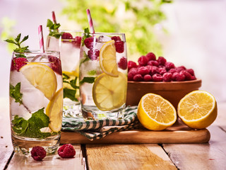 Wooden boards three glasses with alcohol cocktail and ice cubes. Drink number three hundred and fourteen cocktail raspberry mohito with straw and raspberry bowl. Sun morning .Country life.